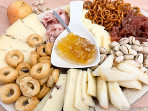 Elegante Charcuterieplatte Elegante Charcuterieplatte in hellen Farben mit Käse, Kochschinken, Crackern, und einer Honigwabe in der Mitte der Platte